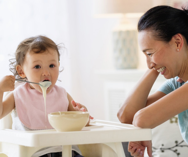 Baby eating cereal in highchair