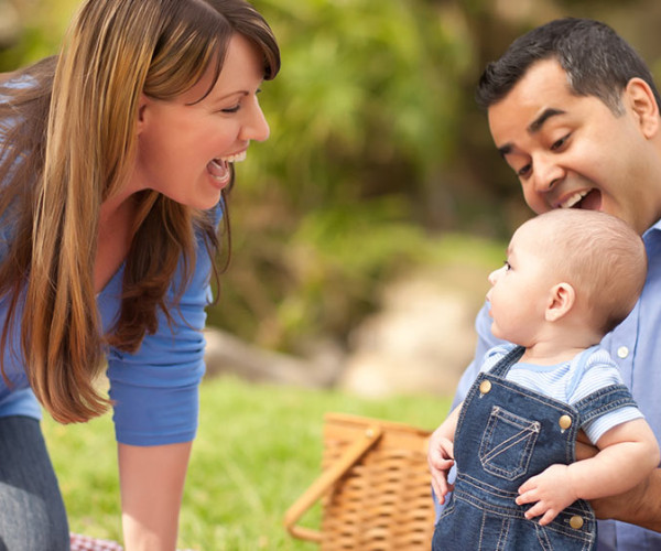Photo of a mother smiling at baby, held by dad